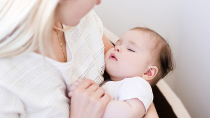Sleeping baby on woman hands in room. Motherhood. Maternity.