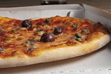 pizza pomodoro acciughe capperi olive nere intera nella scatola dal basso primo piano vista destra