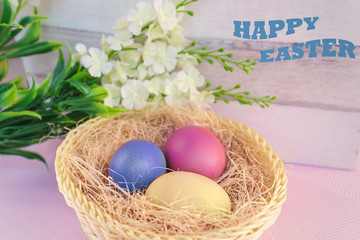 Festive Easter arrangement of flowers and painted eggs in a basket. Soft focus.