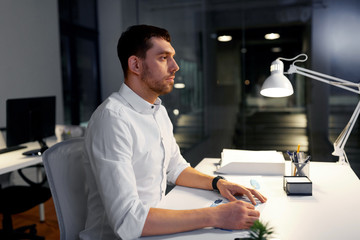 Fototapeta premium business, deadline and people concept - businessman sitting at table at night office
