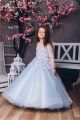 Obraz na płótnie Canvas Cute adorable baby girl in elegant blue wedding dress indoors posing and looking at camera. Childhood, fashion kids concept