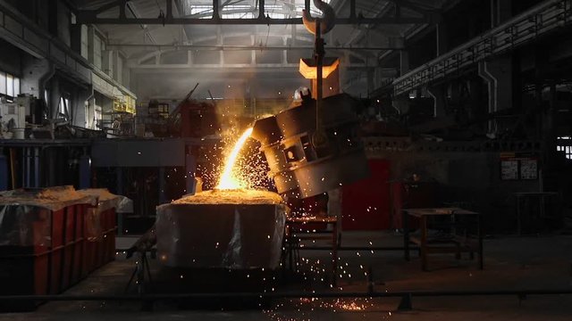 Man working with liquid metal in factory. Metal factory sparks