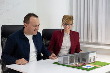 Two architects looking at a model house in office