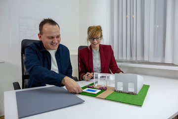 Two architects looking at a model house in office