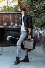 Street musician holding a case with a guitar and amplifier. Descends into the underground passage. Vagrant lifestyle. Playing to make money a living. Unemployed musician. Future rock star.