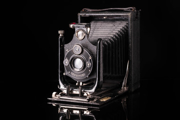 vintage compur camera with reflection on black background