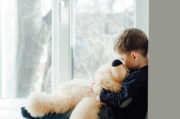 Little sad boy with teddy bear
