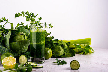 Detox green smoothie in glass at wooden white background.