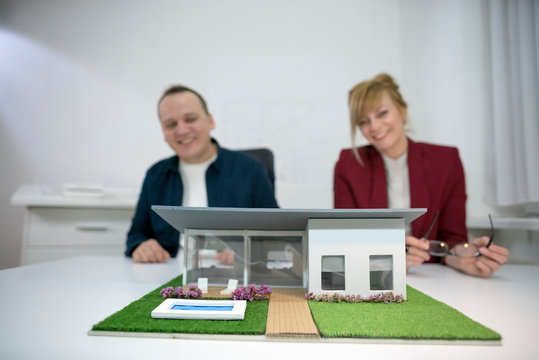 Two architects looking at a model house in office
