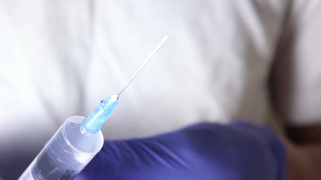Doctor's hands fill the syringe with vaccine, preparing for the injection of the injection to the patient. Hands close up.
