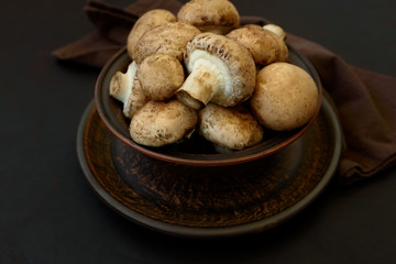 Brown champinon mushrooms (agaricus) in bowl on rustic wooden background. Healthy eating or vegetarian concept. Copy space