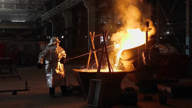 Man working with liquid metal in factory. Metal factory
