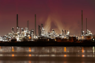 Fototapeta na wymiar Reflection of refineries and its chimney during the on fire sunset golden hour moment at Rotterdam, Netherlands