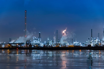 Fototapeta premium Reflection of refineries and its chimney during the on fire sunset golden hour moment at Rotterdam, Netherlands