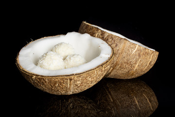 Group of two halves of fresh bio coconut with three small cocoa balls isolated on black glass