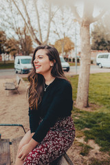 Fashionable young woman sitting on a bench smiling shyly