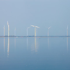 wind turbines and blue sky reflected in water of eemmeer near huizen in holland