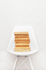 Stack of vintage books and chair on white wall background
