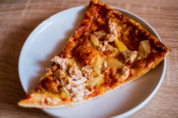 Slice of chicken and pineapple pizza isolated on a white plate 
