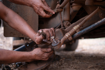 Hands of mechanic fixing wishbone control arm of the truck part to repair front wheel