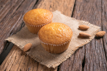 Close up a cup of almond cake against sack fabric on wooden table