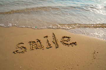 Vacation on the sand beach concept. Smile words written into the sand on the beach at Rayong, Thailand