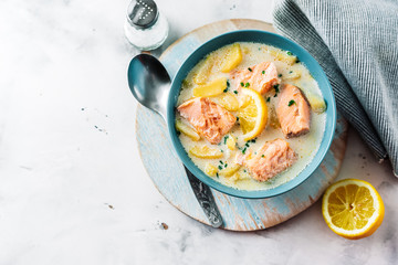 Top view of soup with salmon, cream and potatoes in a blue bowl