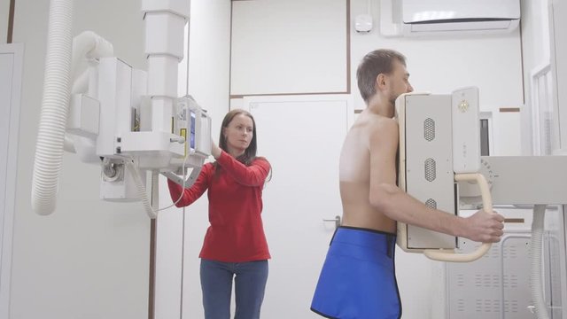 Man at lungs roentgen x-ray examine procedure. Nurse preparation equipment in hospital room for patient. Medicine radiologic machine for the diagnostic health problems and get a quick results