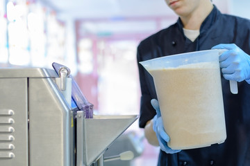 Chef confectioner in uniform producing ice cream with ice cream machine
