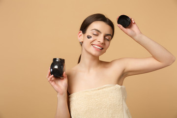 Close up brunette half naked woman 20s with perfect skin, nude make up black mask isolated on beige...