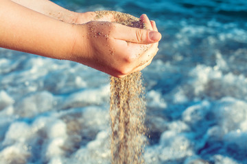Sand falling from the hands on sea beach background. Happy holiday and vacation