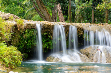 Obraz premium The water flowing over rocks and trees down a waterfall at Kapao waterfall National Park ,Chumphon in Thailand.