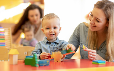 Kindergarten teacher playing with toddler in nursery. Developmental toys for preschool. - 258938987