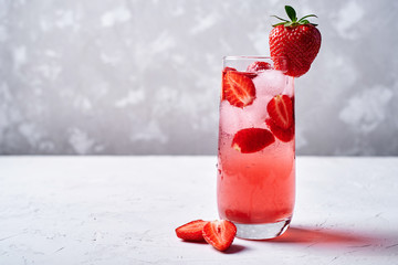 Fresh lemonade with ice, mint and strawberry on top in glass on white table background, copy space....