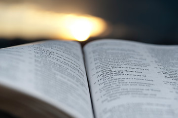 Open Bible with beautiful sunset to the background. Close-up. Horizontal shot.