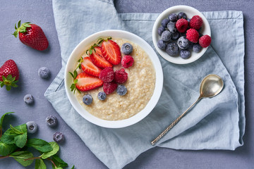 Oatmeal with blueberry, strawberry, raspberry on blue dark background. Top view. Healthy diet breakfast