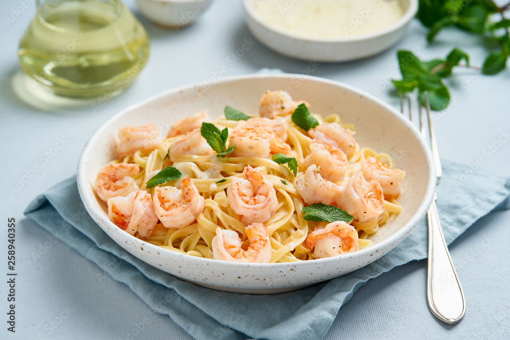 Wall mural Pasta spaghetti with fried shrimps, bechamel sauce, mint leaf on blue table, italian cuisine, side view