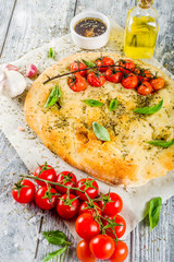 Traditional  homemade Italian flat bread focaccia. Focaccia with tomatoes and basil leaves, wooden background, top view