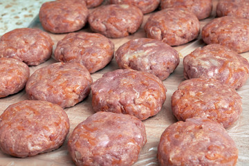 Several rows and lines of fresh not fried cutlets lie on the Board. Prepared for the frying or cooking of raw meat patties. Home-cooked food. Beef is mixed with pork, carrots, onions and spices.