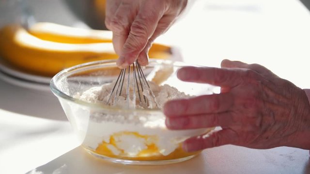 Making pancakes. An old woman mixes the ingredients