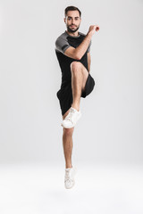 Handsome young sports fitness man posing isolate over white wall background jumping.