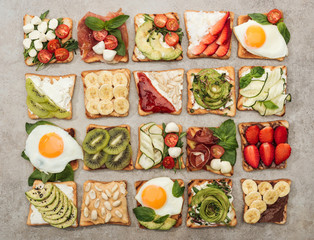 Top view of toasts with fried eggs, cut vegetables and fruits on textured surface