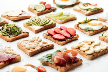 Toasts with cut fruits, fried eggsand peanuts on white