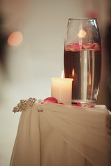 wedding decoration a candle and a vase with water on a white table. Flasks with water and a floating candle