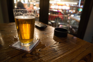 blurred glass of beer on table alcoholism concept