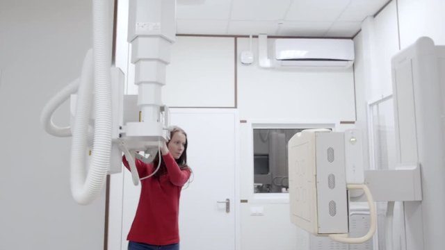 Woman radiologist switch off the automated roentgen diagnostic machine for skeleton scanning. Nurse closing rontgen equipment end of working day. The scene in clinic room for x-ray procedure