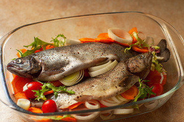 Fresh sea fish with spices and vegetable ingredients on wooden table, cooking concept.