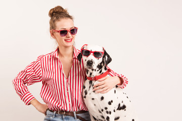 Portrait of happy young woman in good mood sitting with her dalmatian dog. Woman and pet in red...
