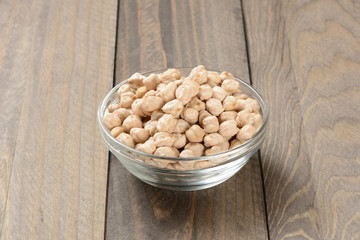 Garbanzos gordos en un cuenco de cristal sobre fondo de madera