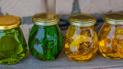 On a wooden shelf there are banks with multi-colored syrups from various plants collected in the mountain forest of the Caucasus. Natural product. Delicacy with original taste. Food photography.